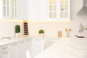 Kitchen with white walls, white cabinets, and white marbled countertops