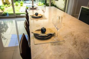 Kitchen island with white/tan/gray granite countertops and three place settings 