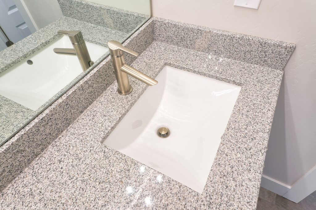 Faucet and single basin undermount sink built in to the gray bathroom countertop.